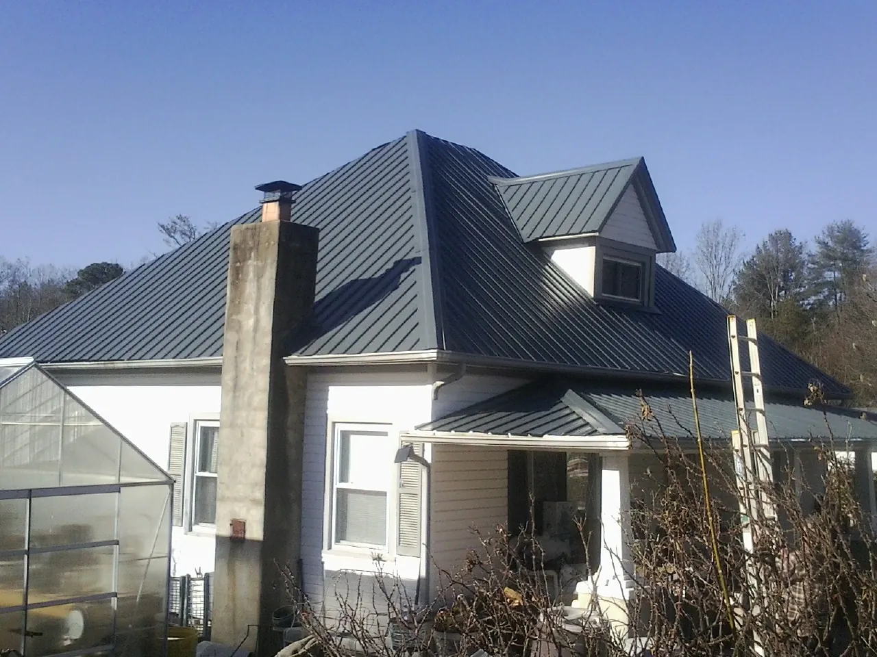 Dark blue standing seam metal roof on a white farmhouse with dormer — Slate & Tile Roof Repair by Roofing Brothers in Ravensdale