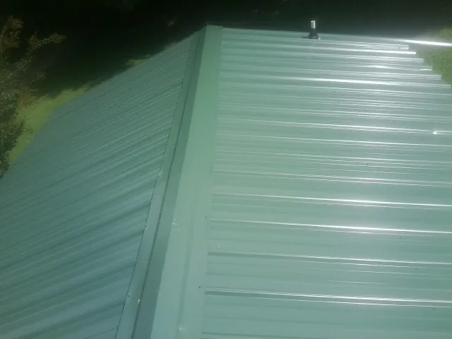 New green metal panels meeting at the ridge of a roof — Flat Roof Repair work by our crew in Ravensdale