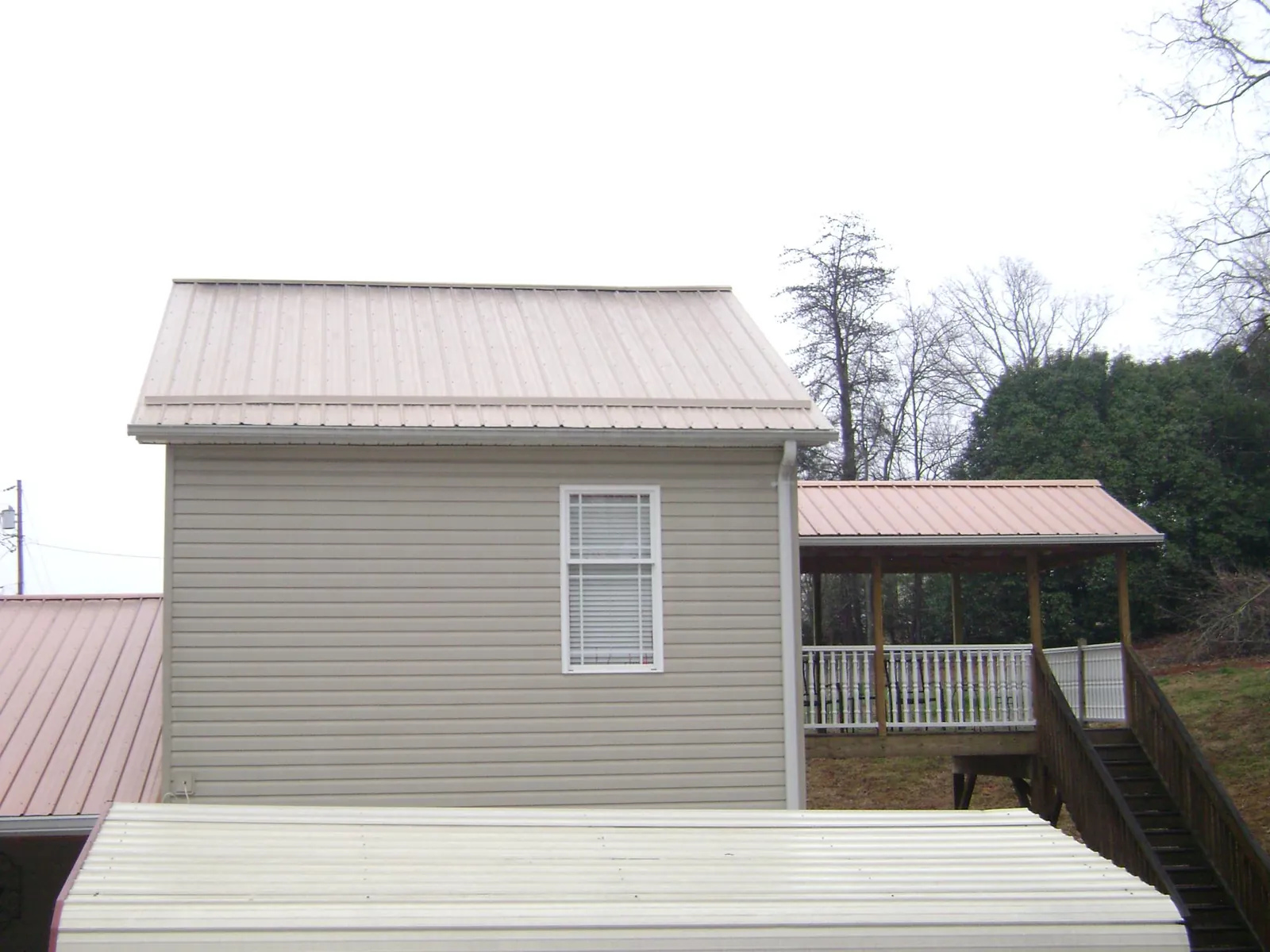 Tan metal roofs on a two story addition and attached porch, from a Roof Replacement job in Ravensdale