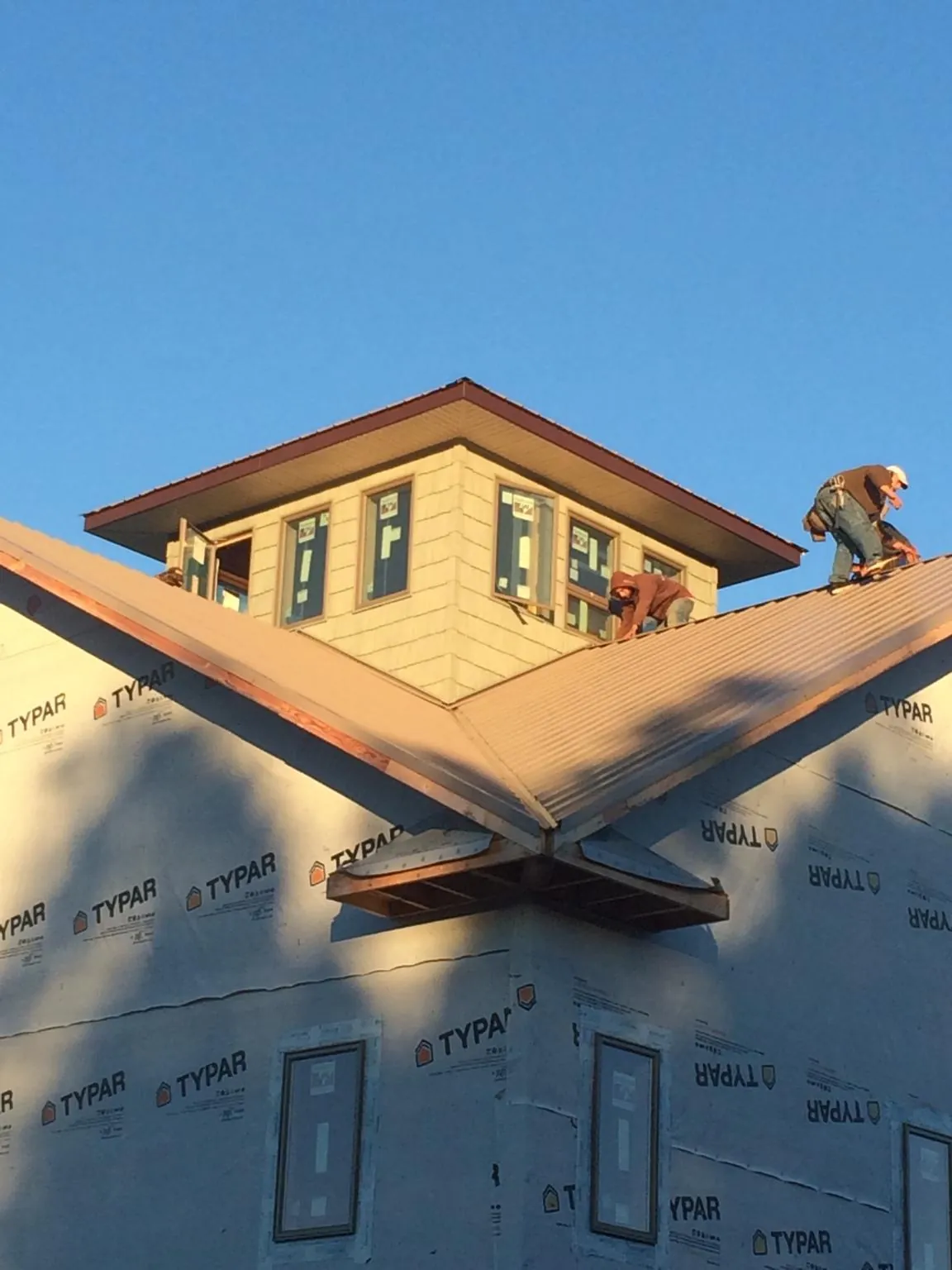Roofers working around a rooftop cupola on a new metal roof at sunset — Roof Waterproofing in Ravensdale by Roofing Brothers